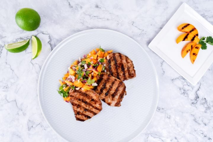 Grilled Pork Chops with Peach Salsa Grilled pork chops with peach salsa with fresh limes and peaches on the side.