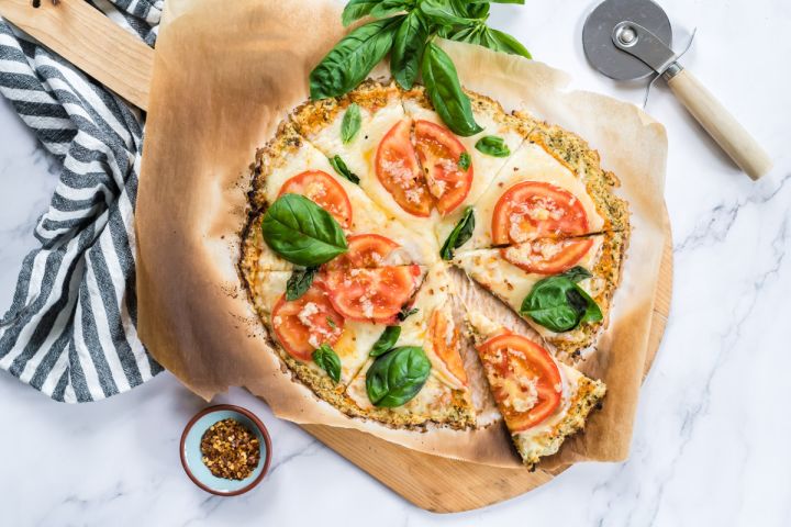 Cauliflower Crust Pizza Cauliflower crust pizza made with cauliflower florets and topped with mozzarella cheese, tomatoes, and basil for a low carb pizza.
