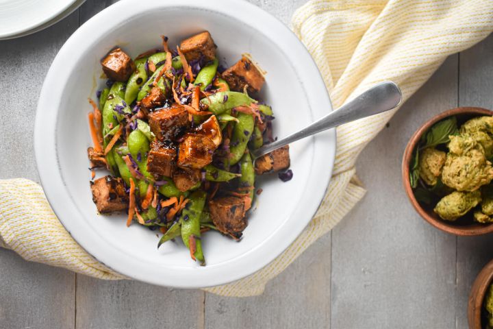 Chili Glazed Tofu with Sugar Snap Peas Chili Glazed Tofu with cabbage, snap peas, carrots, and tofu in a bowl with a napkin.