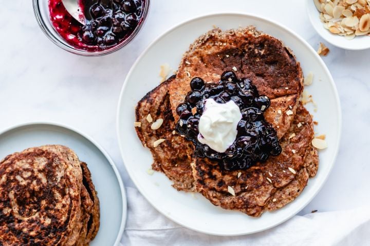 Greek Yogurt and Flax Pancakes with Berries Greek yogurt and flax pancakes on a plate with blueberry compote, whipped cream, and almonds.