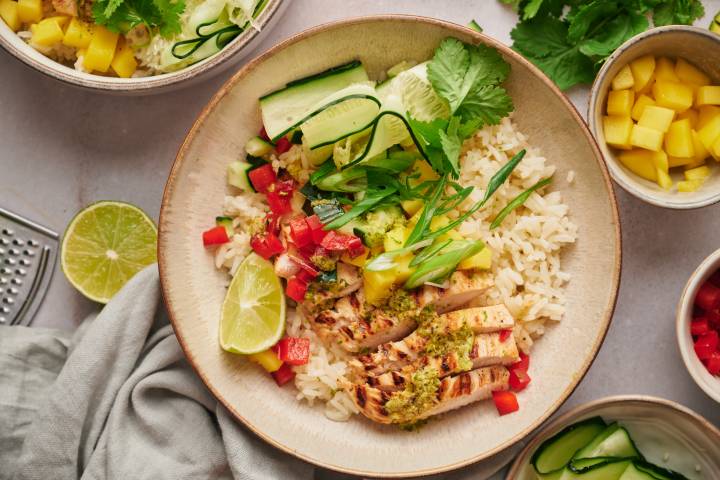 Grilled Chicken Bowls Grilled chicken bowls with citrus grilled chicken breast, rice, mango, red bell pepper, and cucumber in a bowl with cilantro.