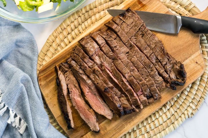 Grilled Flank Steak with Balsamic Marinade Grilled flank steak on a cutting board with a knife.