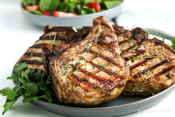 Grilled Pork Chops Grilled pork chops with grill marks and fresh thyme on a plate.