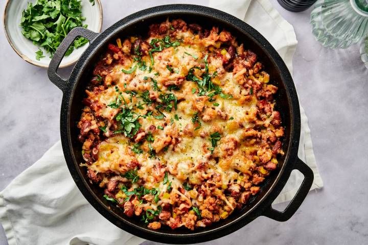 Healthy Taco Casserole Taco casserole with pinto beans, onions, peppers, turkey, corn, salsa, and melted cheese with chips, cilantro, and jalapeno on the side.
