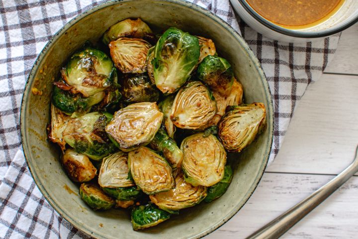Honey Mustard Brussels Sprouts Honey mustard Brussels sprouts in a bowl with the sauce in a small bowl on the side.
