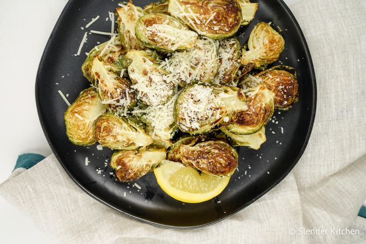 Parmesan Roasted Brussels Sprouts Parmesan Brussels Sprouts with lemon on a plate with a linen napkin.