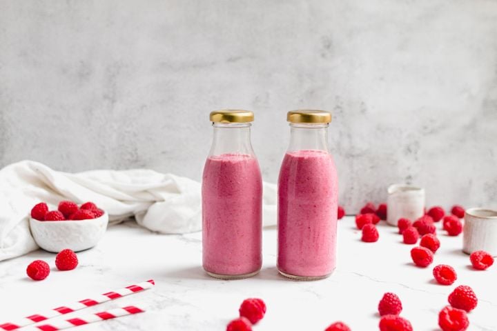 Raspberry Chia Smoothie Raspberry chia smoothie with raspberries, chia seeds, almond butter, and almond milk in two glass bottles.
