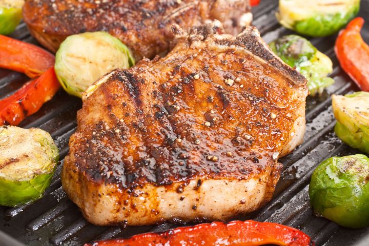 Southwestern Grilled Pork Chops Grilled pork chops with southwestern seasoning on a grill with brussels sprouts and peppers.