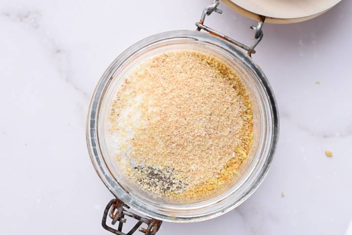 How To Make Lemon Pepper Seasoning Garlic powder and onion powder being added to lemon zest and pepper in a jar.