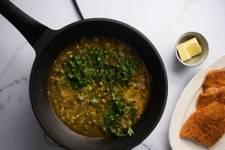 Pan Seared Cod White wine pan sauce with capers and garlic in a skillet.
