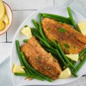 Pan Seared Tilapia with Green Beans Tilapia with green beans, garlic, lemon, and a homemade spice rub on a plate.