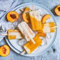 Peaches and Cream Popsicles Peaches and cream popsicles with fresh peaches, honey, and Greek yogurt on a plate with ice and fresh peaches.