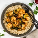 Thai Basil Shrimp Stir Fry Thia baisl shrimp stir fry with zucchini, cooked shrimp, and brown rice in a bowl.