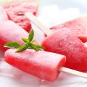 Healthy Watermelon Popsicles Two watermelon popsicles with a block of ice.
