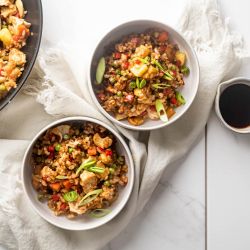 Chicken and Pineapple Fried Rice Chicken pineapple fried rice served in two bowls with fresh pineapple, chicken breast, brown rice, and vegetables with cashews.