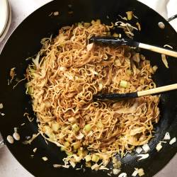 Healthy Chow Mein (Panda Express Copycat) Healthy chow mein with cabbage, noodles, and celery in soy sauce in a wok.
