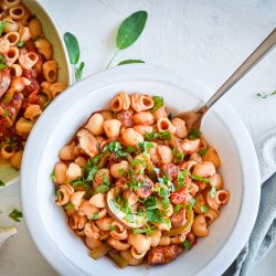 Sausage and Pepper Pasta Shells Sausage and pepper pasta with turkey sausage, bell peppers, onions, mushrooms, and tomato sauce in two bowls with garlic.