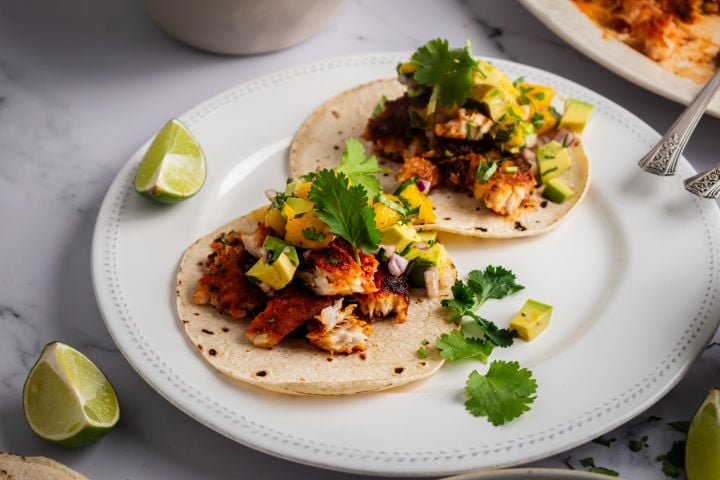 Blackened Fish Tacos Blackened fish tacos with mango avocado salsa on corn tortillas with fresh cilantro and lime wedges.