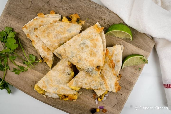 Frozen Breakfast Quesadillas Breakfast quesadillas with eggs, corn, black beans, and cilantro on a cutting board.