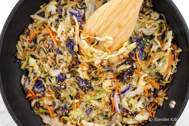 10 Minute Cabbage Stir Fry Cabbage stir fry in a black skillet with sliced green cabbage, carrots, and soy sauce.