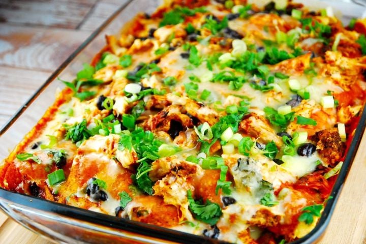 Chicken Enchilada Casserole Chicken enchilada casserole with green onions and olives in a baking dish.