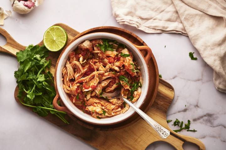 Chicken Tinga (Slow Cooker, Instant Pot, or Stovetop) Chicken tinga in a bowl with onions, cilantro, avocado, and queso fresco.