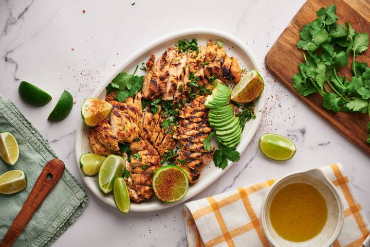 Chili Lime Chicken Chili lime chicken breast sliced and served on a wooden cutting board with lime and cilantro.