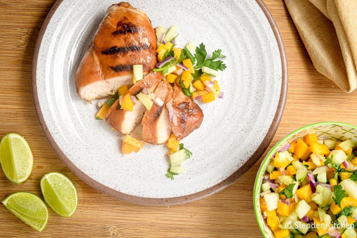 Grilled Chicken with Peach Cucumber Salsa Grilled chicken with peach and cucumber salsa sliced on a plate.