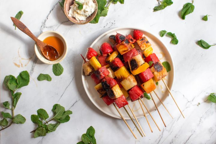 Grilled Fruit Kabobs Grilled fruit kabobs with banana, watermelon, strawberries, and mango on wooden skewers with honey and mint.