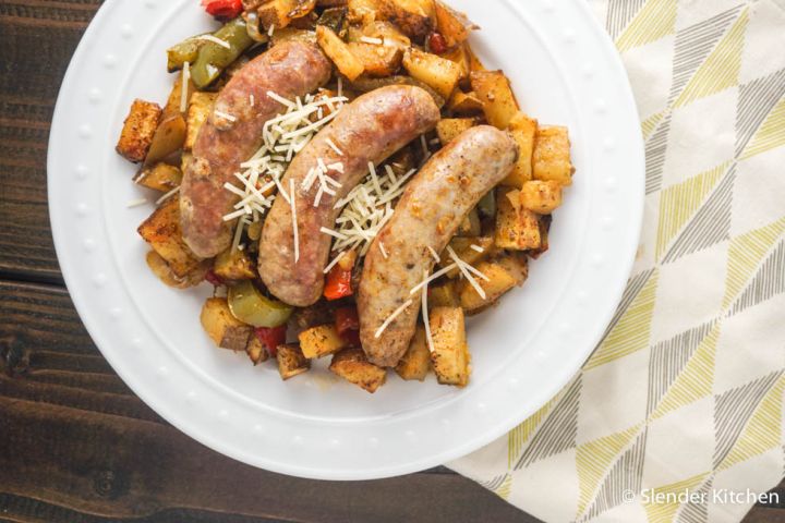 Roasted Italian Sausages with Potatoes, Peppers, and Onions Roasted sausages with potatoes, peppers, and onions on a plate with Parmesan cheese.