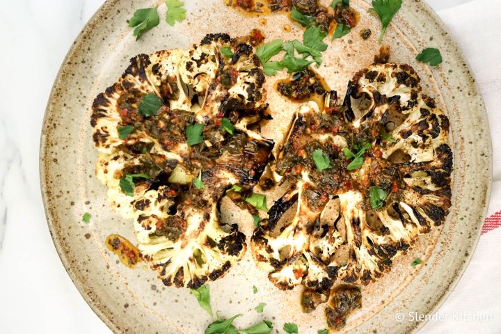 Roasted Cauliflower Steaks Roasted cauliflower steaks with chimichurri sauce drizzled on top.