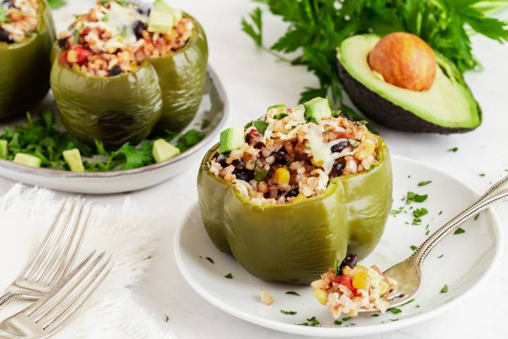 Slow Cooker Vegetarian Barbecue Stuffed Peppers Slow cooker barbecue stuffed peppers with rice, beans, corn, onions, and diced avocado on a plate.
