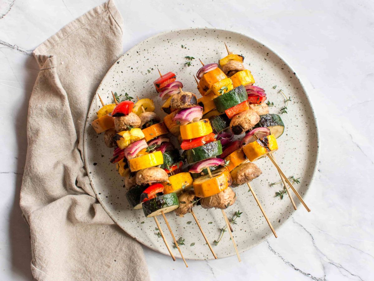Grilled Vegetables Grilled vegetable skewers seen from above on a beautiful round plate pictured on a marble top table.