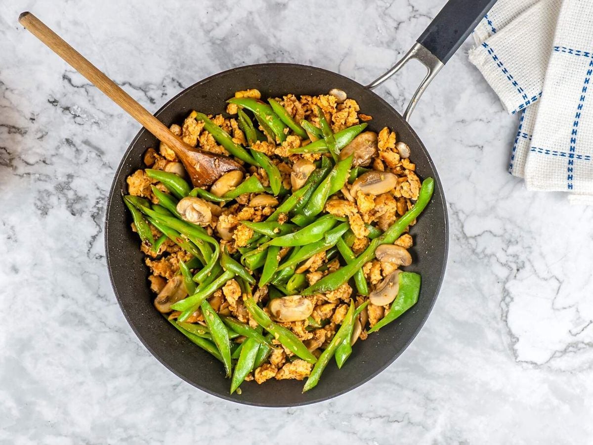 Healthy Stir Fry Recipes Ground Turkey stir fry with green beans and mushrooms in a black skillet with a wooden spoon.