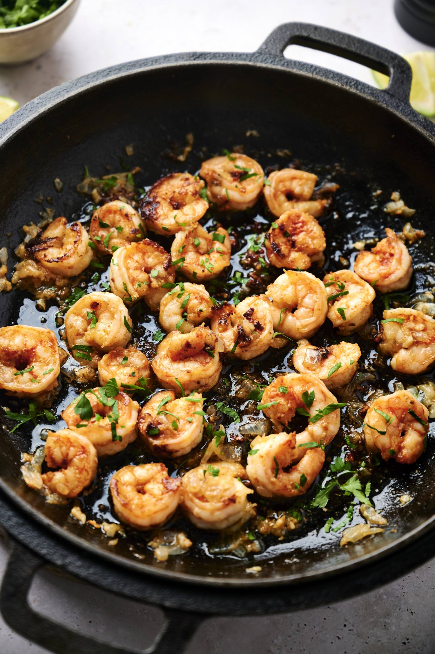 Garlicky Mexican shrimp in a skillet with parsley, minced garlic, onion, and lime juice.