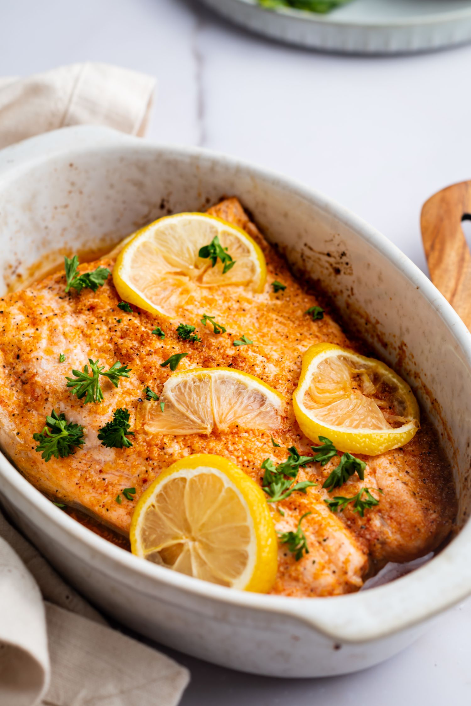 Baked salmon with lemon pepper seasoning served with lemon sliced and fresh parsley.