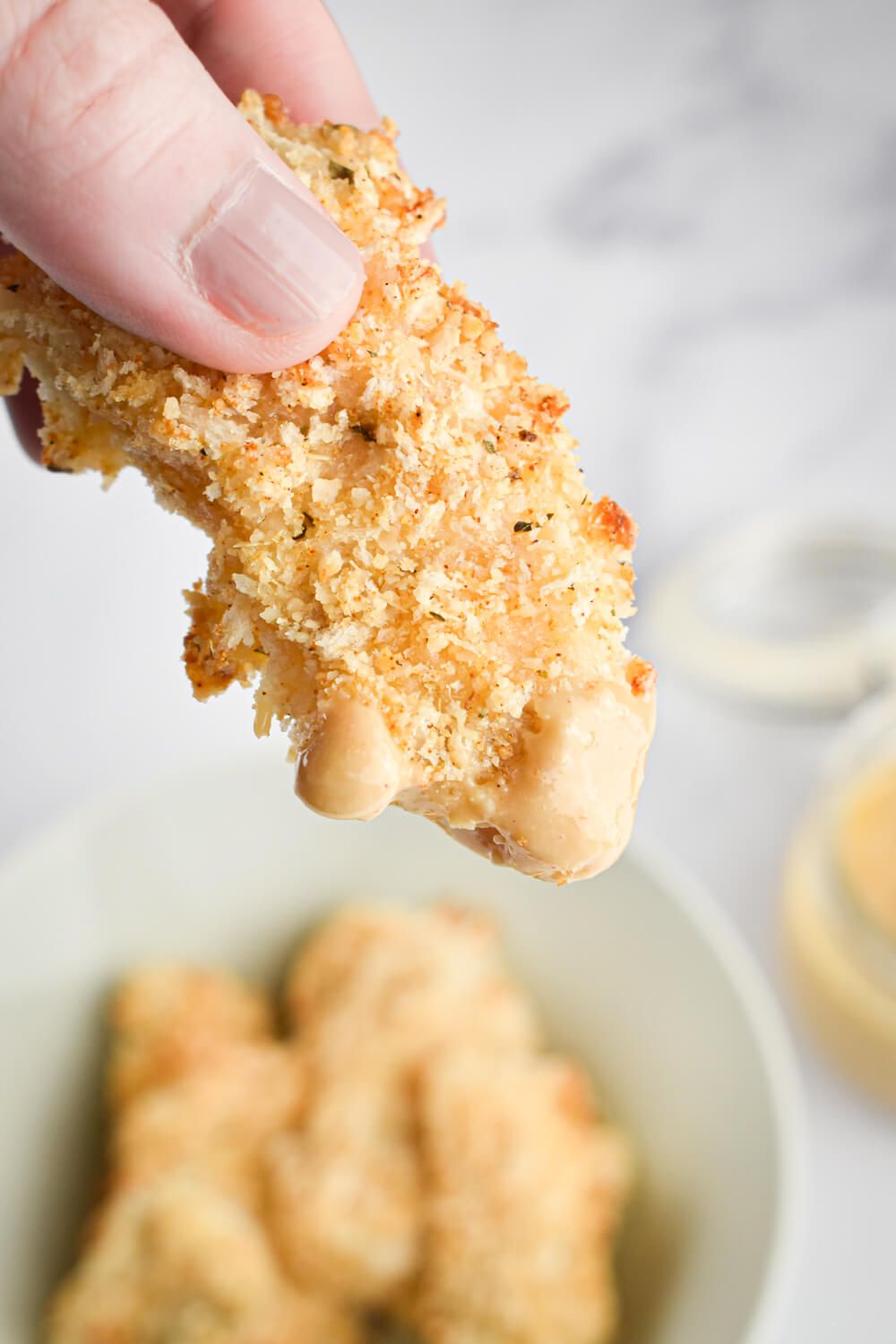 Baked fish sticks with Parmesan cheese being dipped into healthy honey mustard sauce.