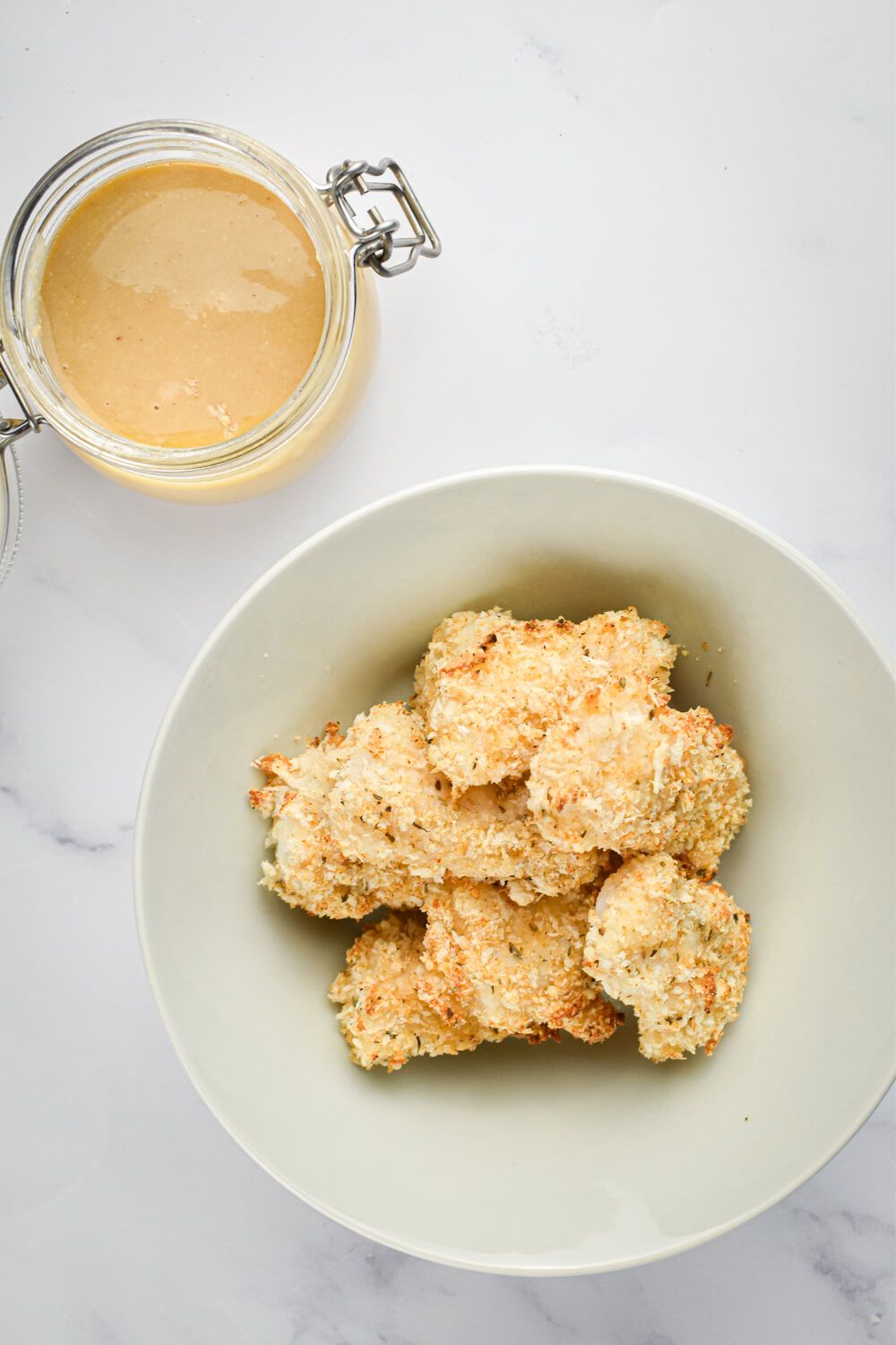 Crispy homemade fish sticks with a crispy coating on a plate with dipping sauce on the side.