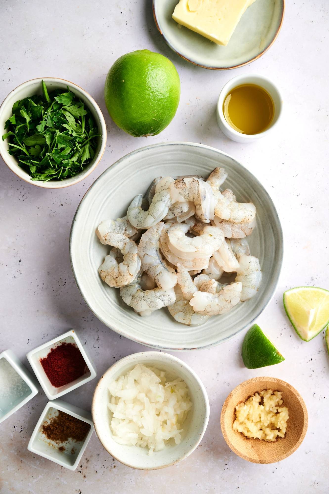 Ingredients for Mexican Garlic Shrimp including raw shrimp, onion, garlic, butter, parsley, and spices.