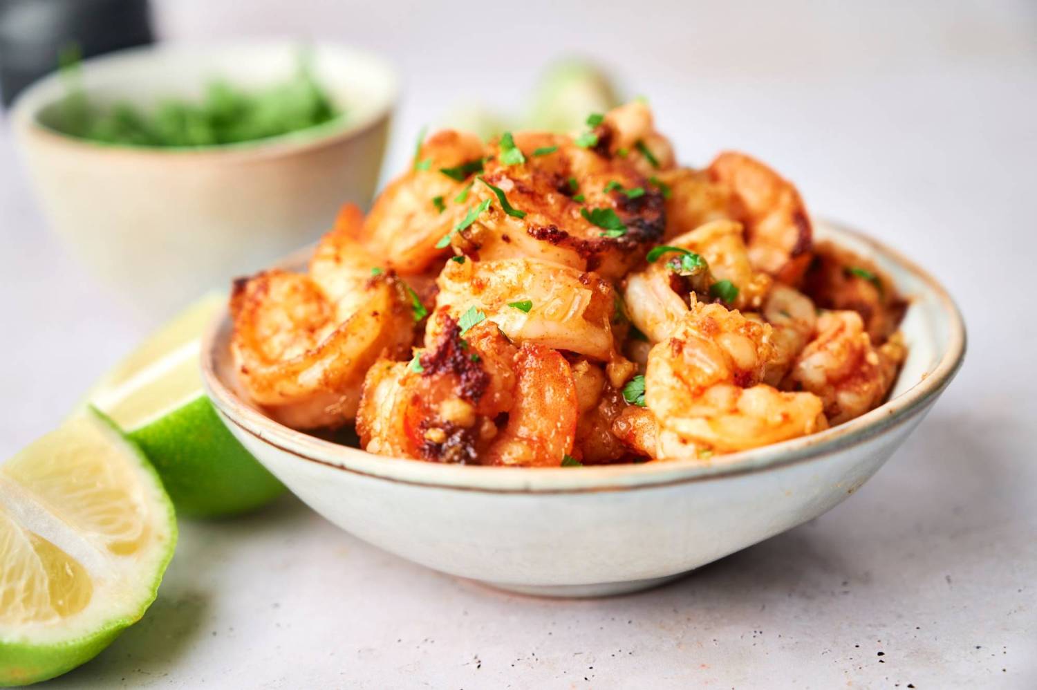 Mexican camarones al mojo de ajo served in a bowl with lime juice and parsley.