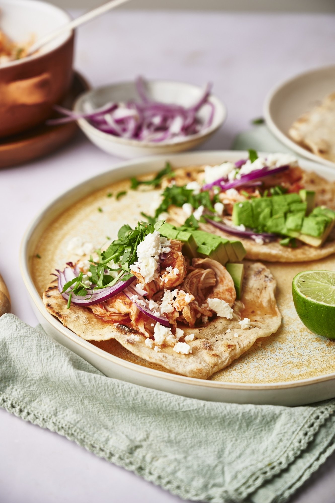 Tacos with chicken tinga served in corn tortillas with cheese, onion, cilantro, and limes.
