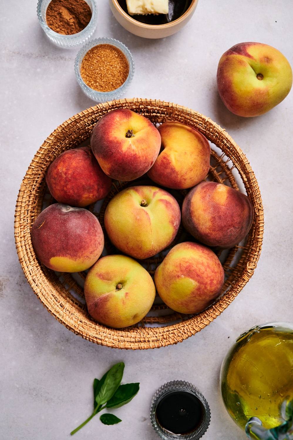 Ingredients for grilled peaches including fresh peaches, brown sugar, butter, cinnamon, basil, and balsamic vinegar.