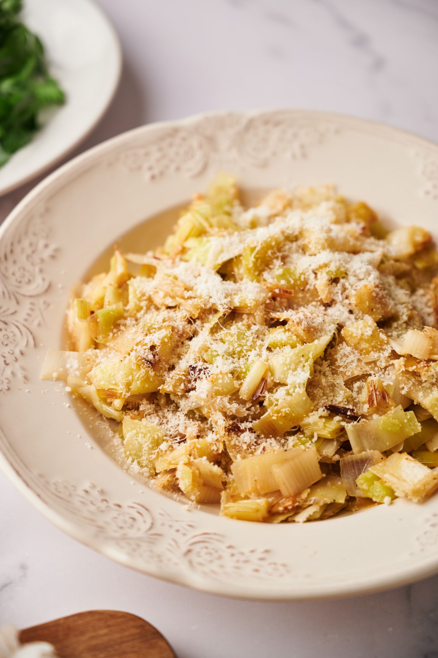 Bowl of sauteed leeks with garlic, butter, Parmesan cheese, and black pepper.