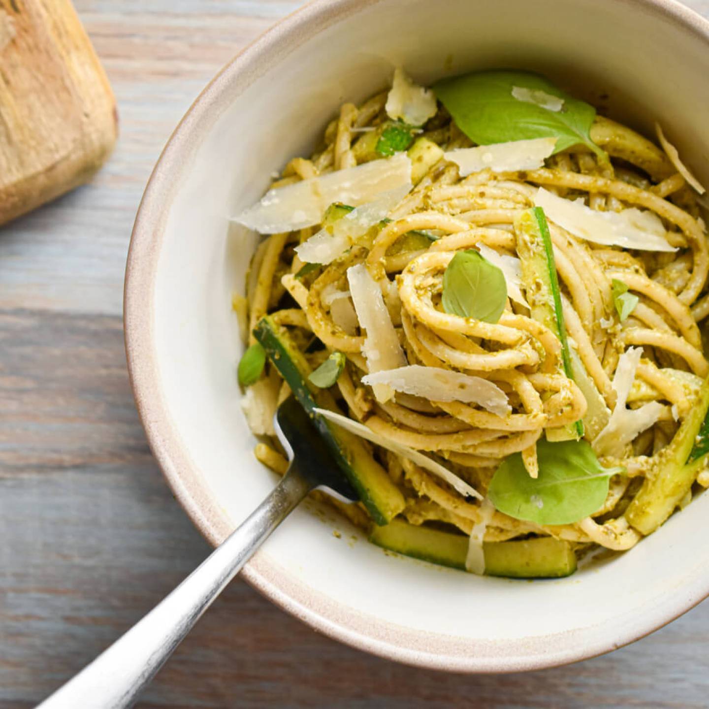 Creamy pesto pasta with zucchini, basil pesto, and Parmesan cheese in a ceramic bowl.