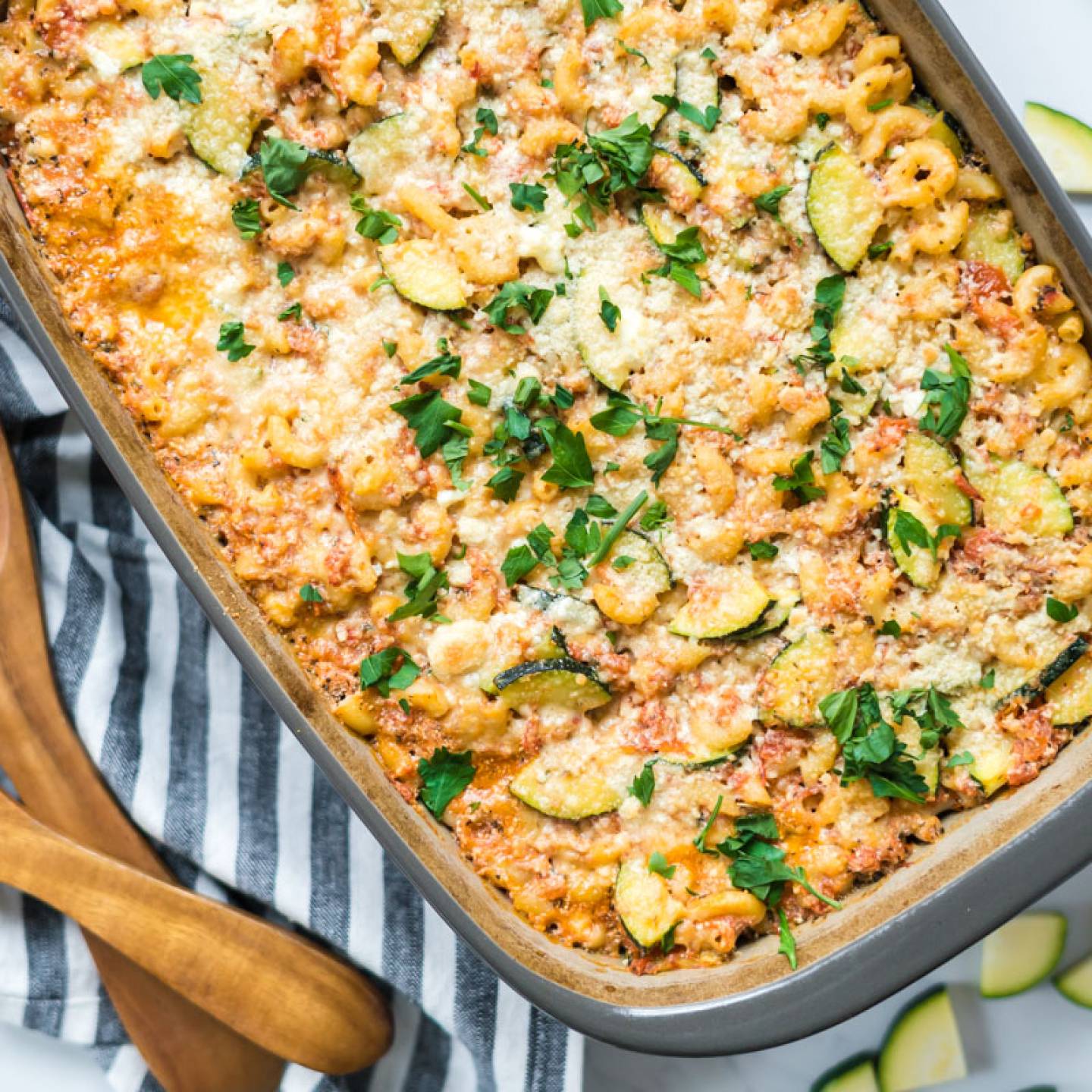 Baked zucchini pasta in a baking dish with melted cheese and zucchini slices.