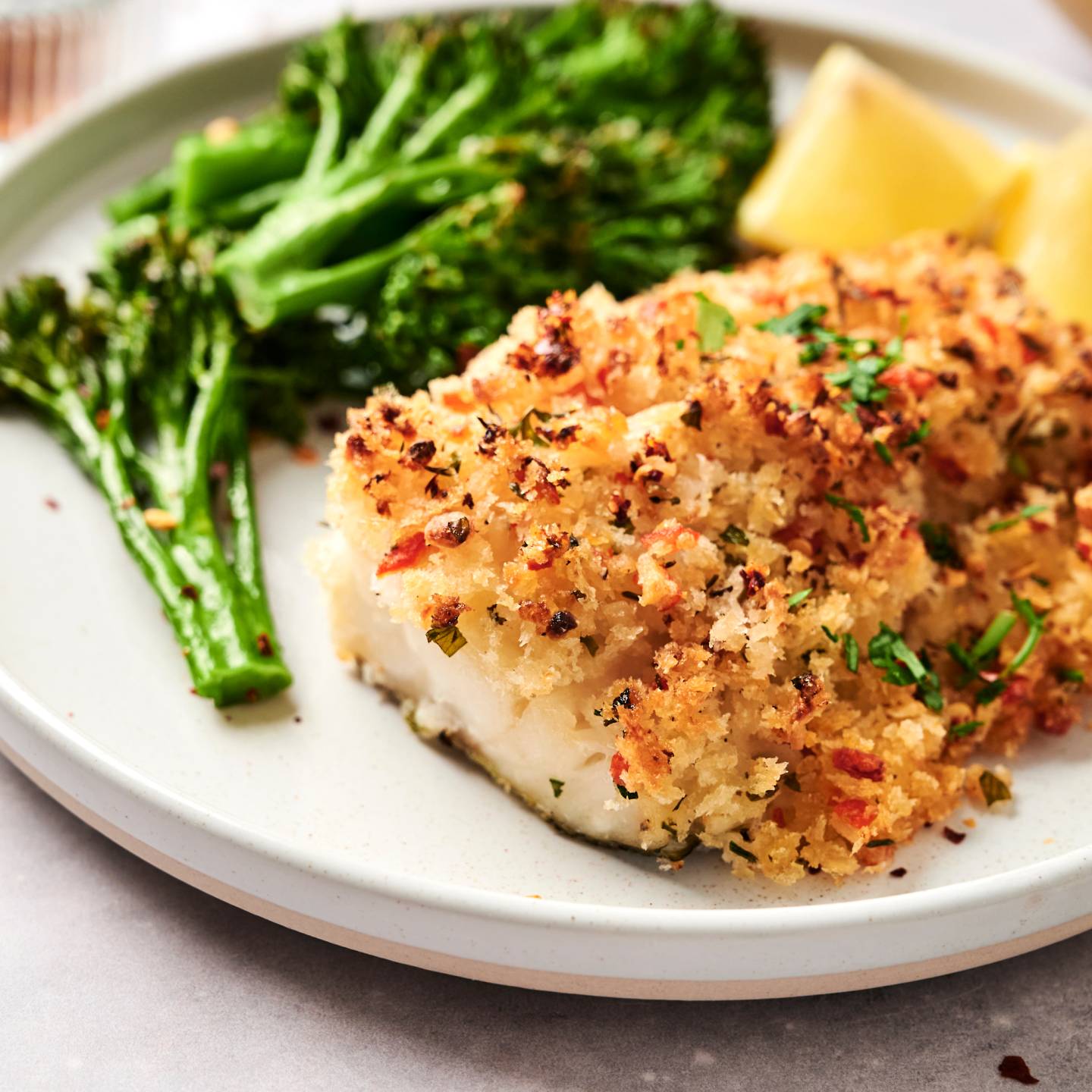Baked haddock with seafood stuffing served with broccoli and lemon wedges.