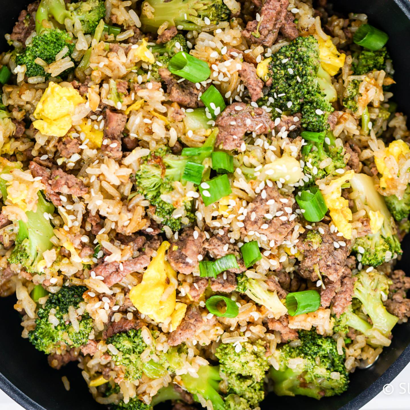 Beef and broccoli fried rice with eggs in a skillet.