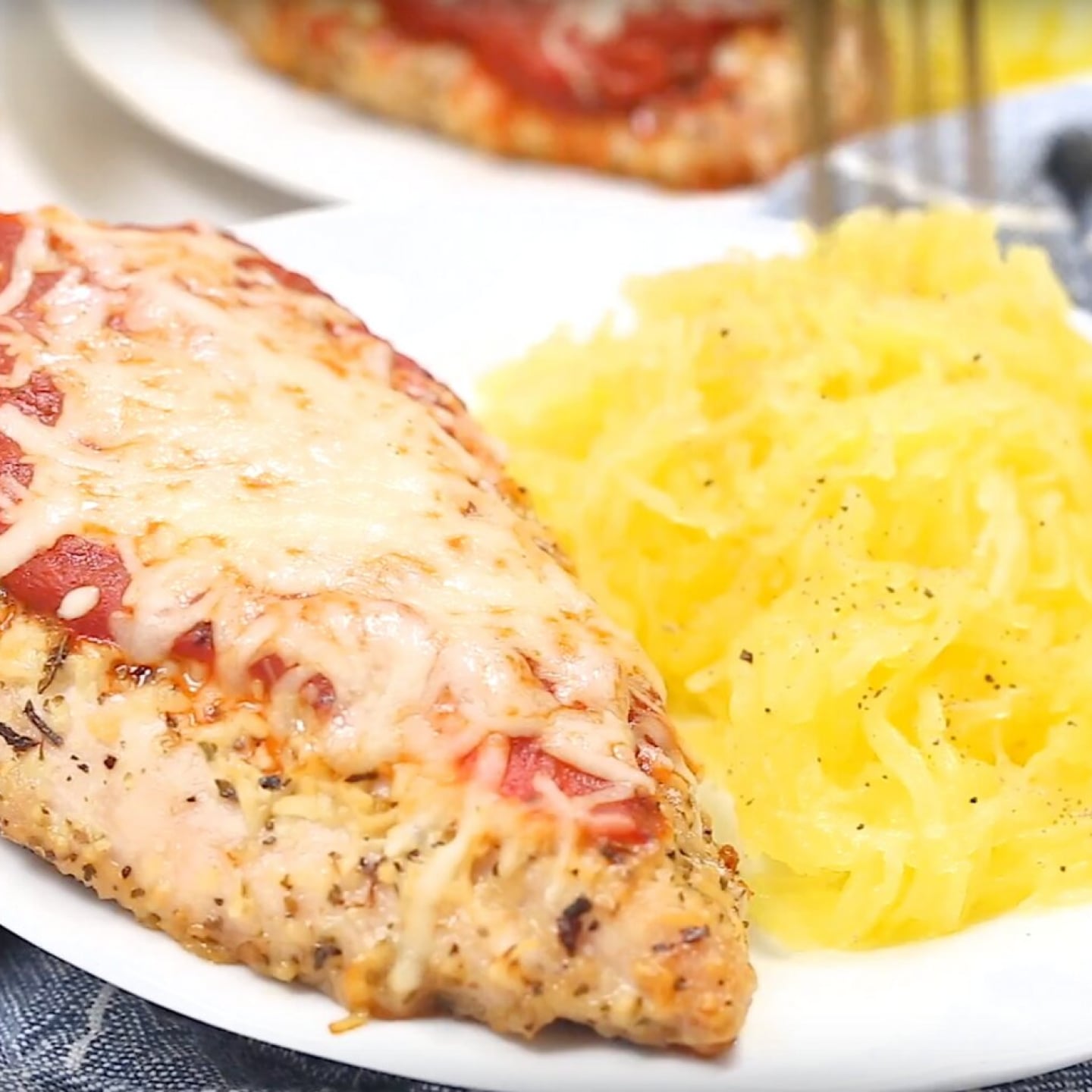 Spaghetti squash chicken parmesan on a plate with a blue napkin and fork.