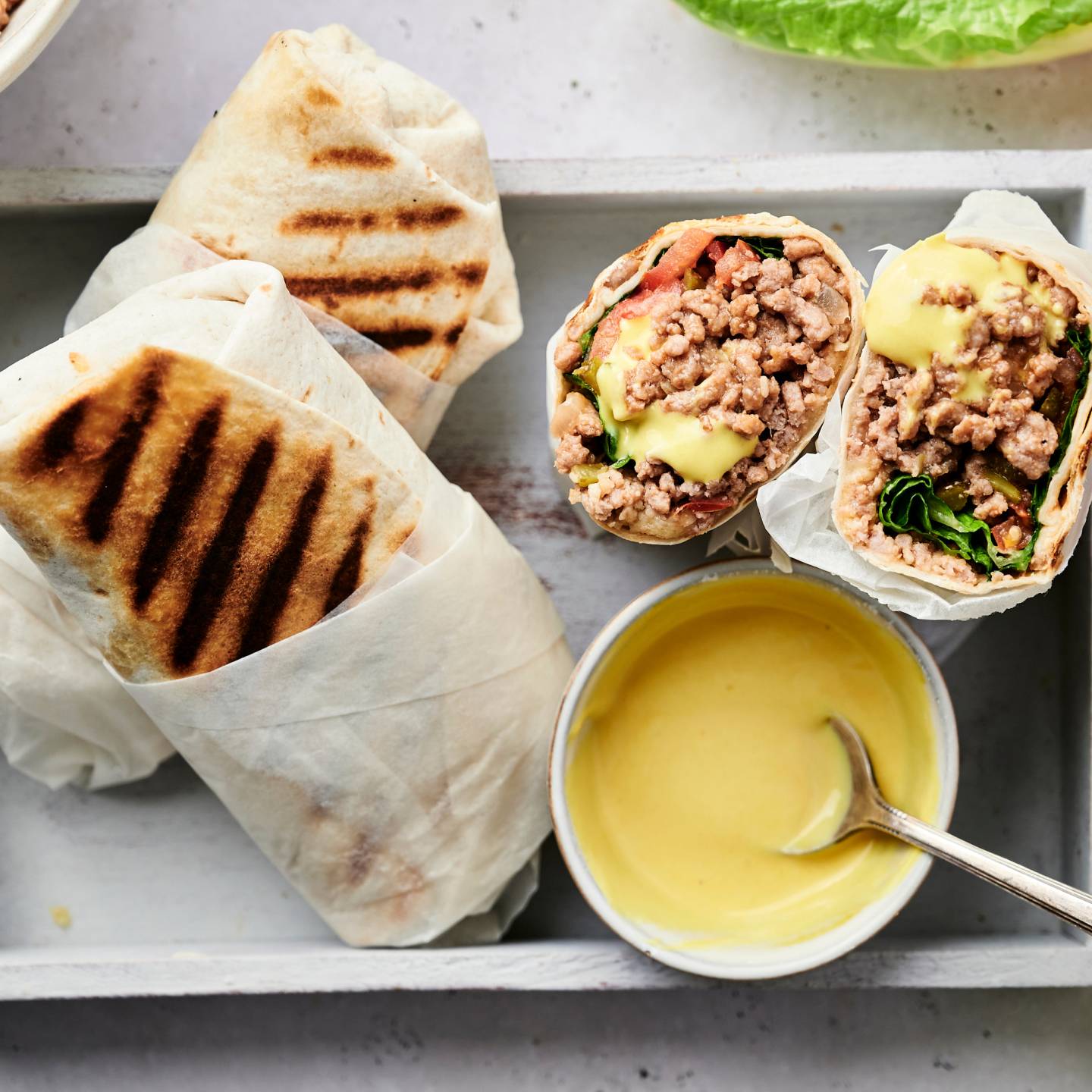 Cheeseburger wraps in a tortilla with ground beef, lettuce, and tomatoes served with homemade burger sauce.