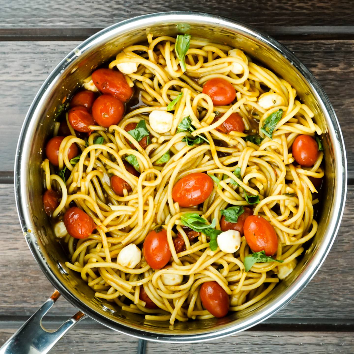 Caprese pasta in a pot with cherry tomatoes, mozzarella cheese, and basil.